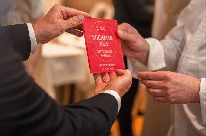Two people hold a red Michelin plaque for the 2025 Restaurant Haerlin award in their hands