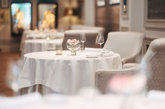 The elegant interior of the Haerlin*** restaurant features round tables covered with white tablecloths and set with glasses and napkins.