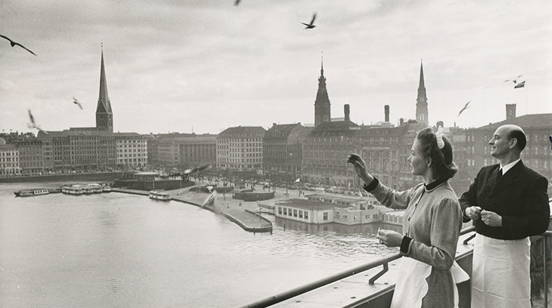 Historische schwarzweiß Aufnahme von zwei Personen auf einer Terrasse des Hotel Vier Jahreszeiten in Hamburg