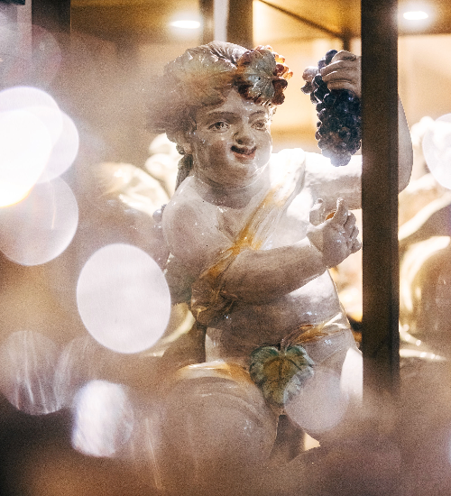 Artistic cherub holding grapes in the light